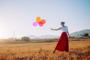 beautiful woman holding colorful balloons in the field